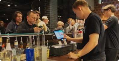 skuteczniejsze-zarzadzanie-pracownikami Barman obsługujący klientów w barze za pomocą systemu POSbistro, który wspiera w efektywnym zarządzaniu sprzedażą i personelem.