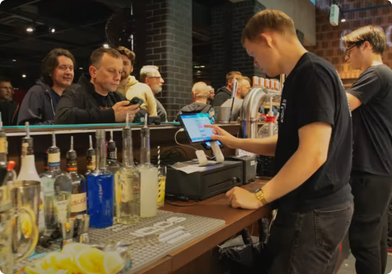 system-pos-do-klubow-kaucja-kubki Barman obsługujący klientów przy barze z systemem POSbistro